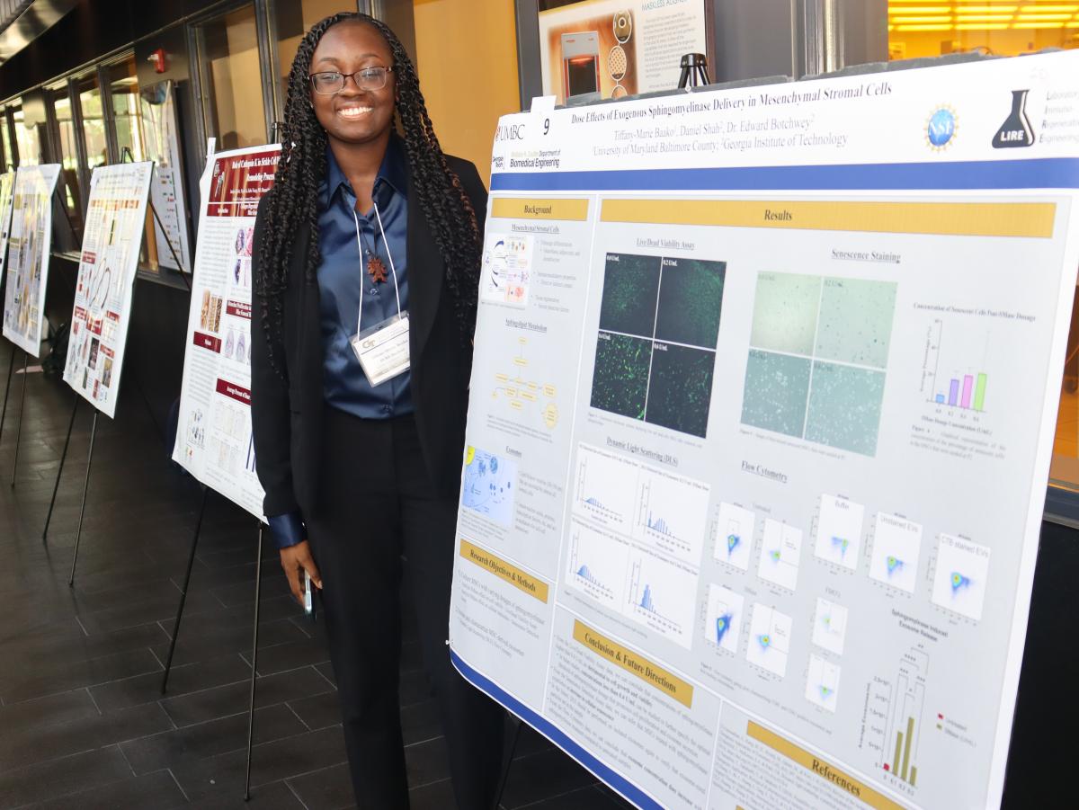 A female student standing in front of their poster.