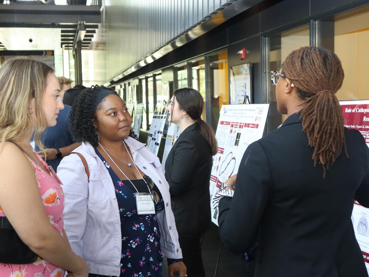 Three students engaged in a poster session presentation.